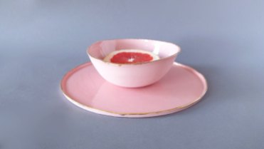 Still life photo of two pastel pink plates with a red orange.