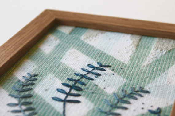 Still life photo of a framed abstract textile art with geometric forms, detail view.