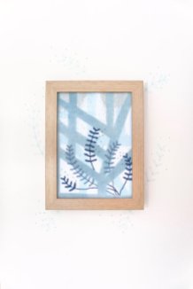 Still life photo of a framed abstract textile art with geometric forms, frontal view.