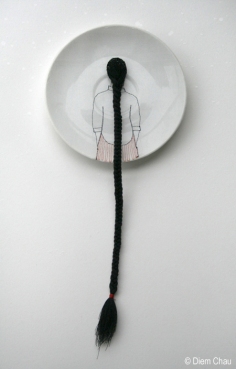 Still life photo of a porcelain plate seen from above with an illustration if a girl seen from her back with a long braid.
