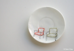Still life photo of a porcelain plate seen from above with an illustration of two chairs.
