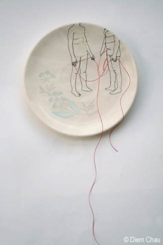 Still life photo of a porcelain plate seen from above with an illustration of two people holding a red thread.