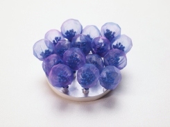 Still life photo of a purple brooch realised with semi transparent and translucent textiles, the shape reminds natural and organic forms taken from nature.