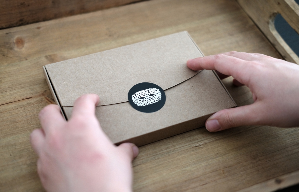 Still life photo of a brown paper box with hands holding it.