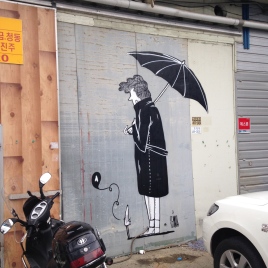 Photo of a grey wall decorated with an illustration of a man seen from its back holding an umbrella.
