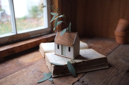 Still life of a tiny cottage putted over a book.