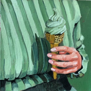 Female hand holding a green gelato cone dressed in green.
