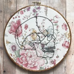 Still life photo of an hand embroidered skull over a floral textile.